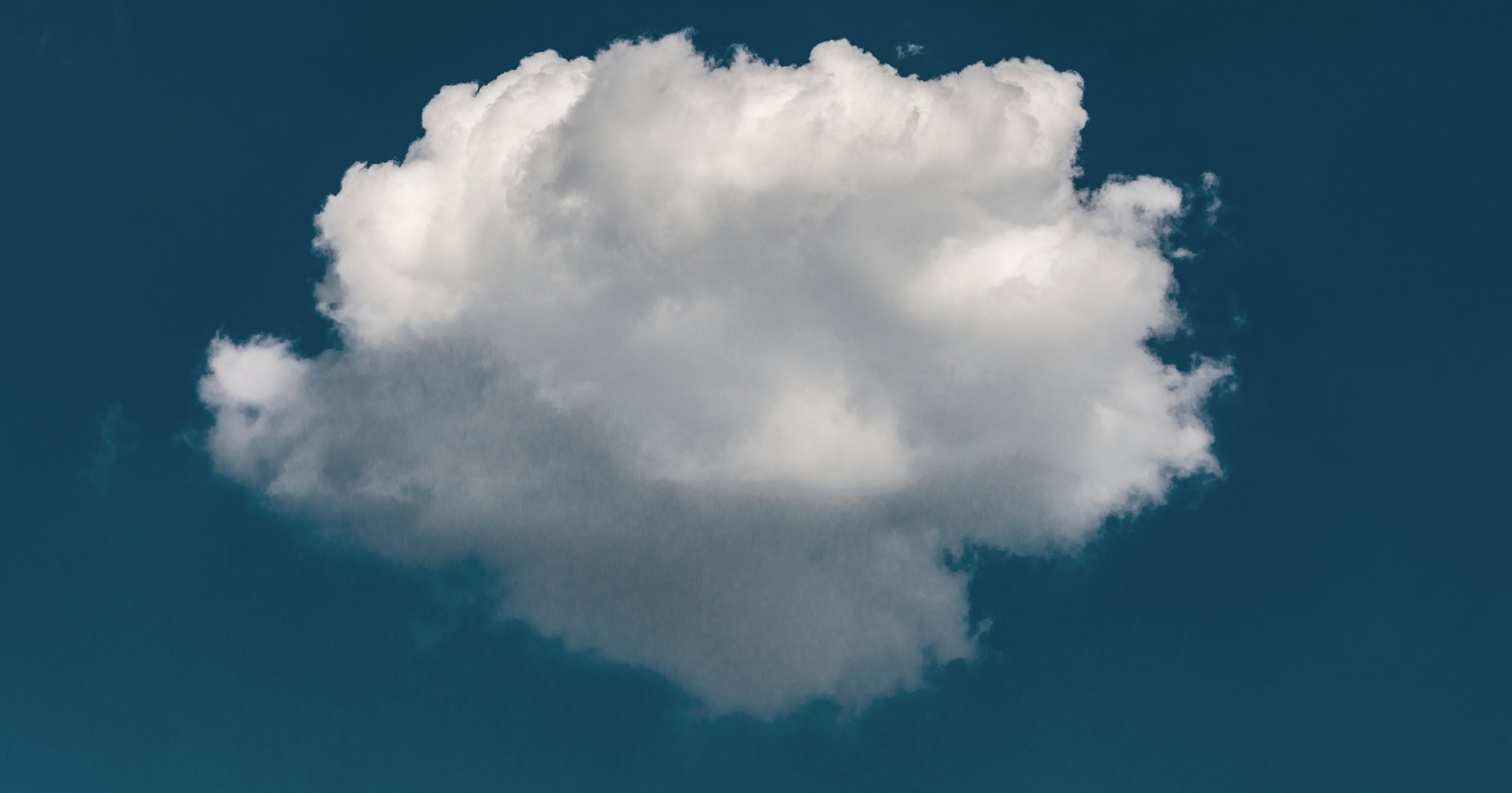 A single white puffy cloud against a bold blue sky.