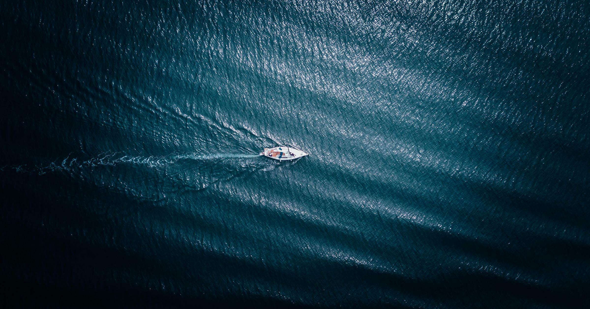 A top-down aerial photo of a sailing ship in deep blue water