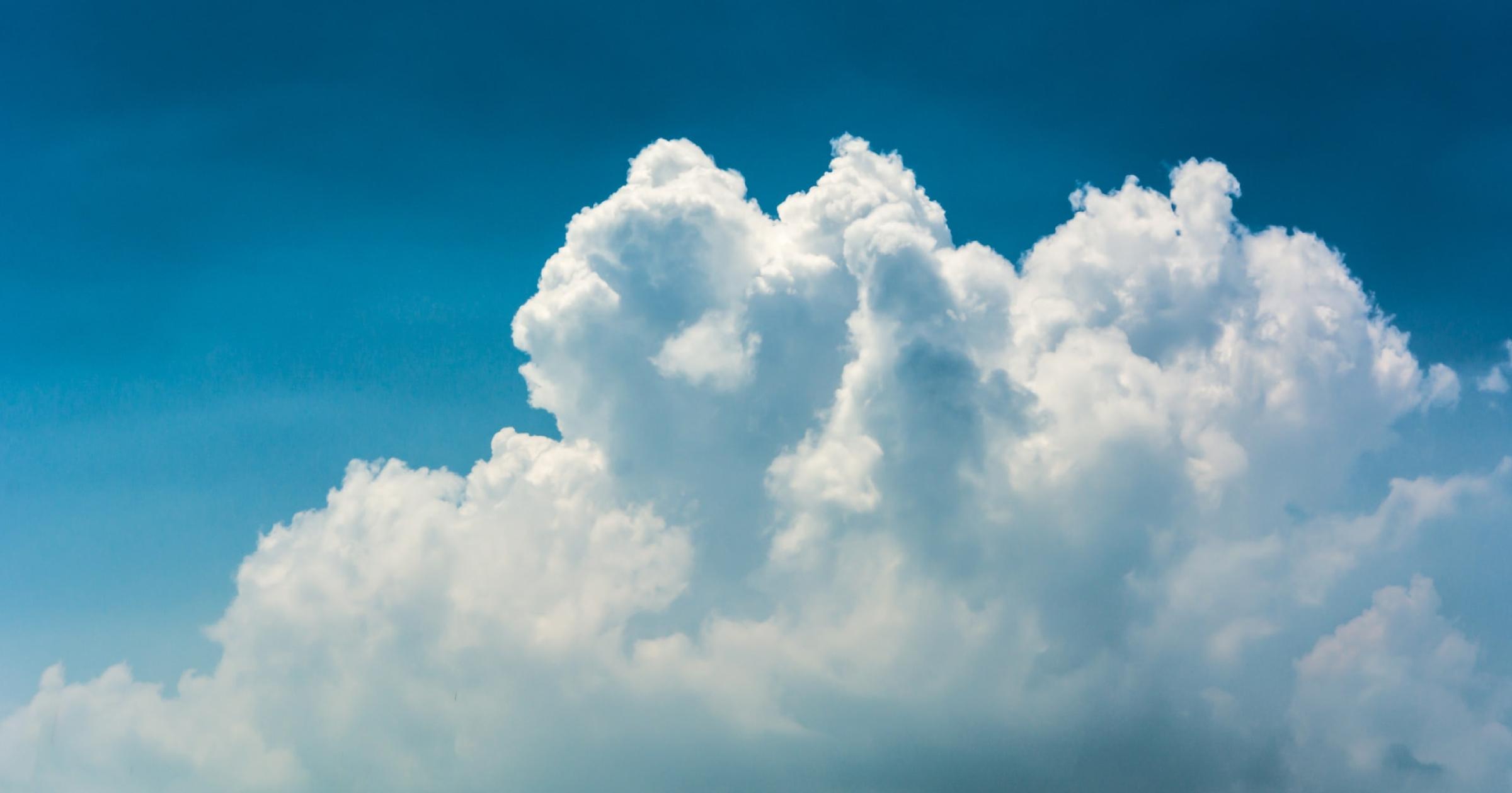 Tall white column of clouds against a bright blue sky.